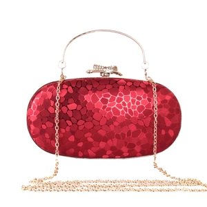 Detail of red water cube evening bag with gold handle and sparkling rhinestone bow clasp