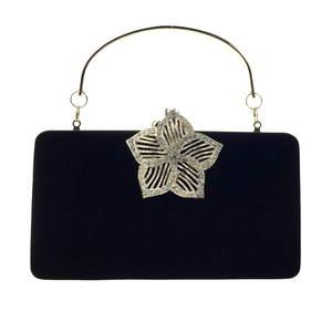 Détail d'une pochette en velours noir avec boucle fleur dorée sertie de strass
