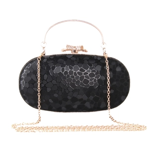 Close-up of black stone-textured clutch with gold handle and rhinestone bow clasp