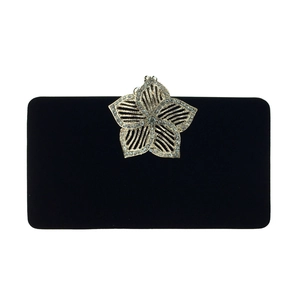 Détail de la pochette en velours noir avec fermoir fleuri doré et strass brillants