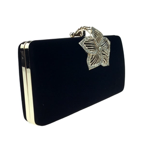 Détail du fermoir fleur dorée avec cristaux sur une pochette de soirée en velours noir