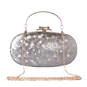 Detail of silver evening clutch featuring geometric scale texture and diamond bow clasp