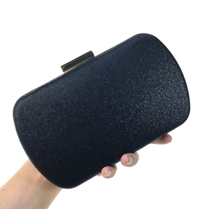 Detail of the navy blue glitter surface and metal clasp on the rectangular clutch bag