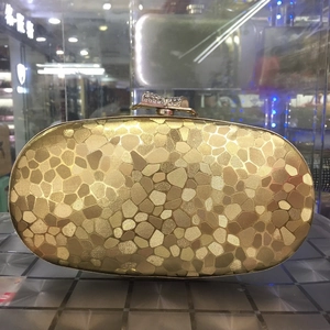 Detail of gold oval evening clutch bag with sequin mosaic texture and crystal bow clasp
