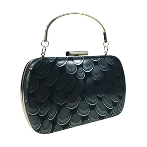 Macro view of peacock-patterned evening clutch bag with golden metal handle and top clasp