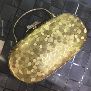 Detail of evening clutch bag with gold sequin texture and rhinestone bow metal handle