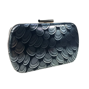Macro view of peacock scale pattern and golden metal clasp on evening clutch bag