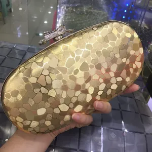 Macro detail of golden hard shell evening clutch with rhinestone bow and pebble texture