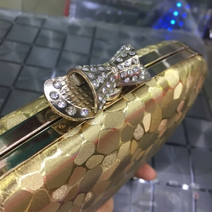 Detail of golden evening bag with hexagonal texture and rhinestone bow clasp