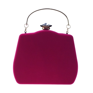 Macro shot of fuchsia velvet clutch bag with a large crystal clasp and gold ring handle