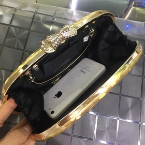 Golden embossed evening clutch with rhinestone bow clasp and spacious black satin interior