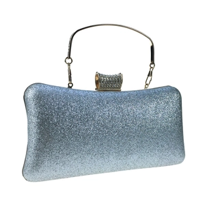 Close-up of silver glitter evening clutch with rhinestone lock and gold metal handle