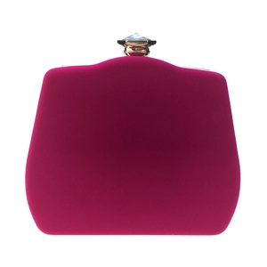 Close-up of fuchsia velvet evening clutch with a luxury crystal-encrusted gold clasp