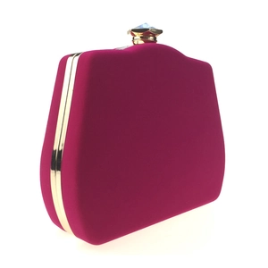 Macro detail of fuchsia velvet evening bag with gold metal frame and blue gem clasp