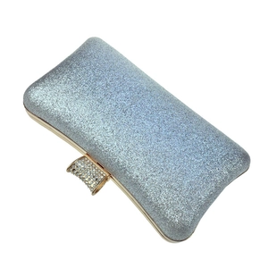 Detail of silver sequin evening clutch bag with gold trim and rhinestone-encrusted clasp