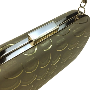 Detailed view of dark gold peacock pattern clutch bag with silver rectangular clasp