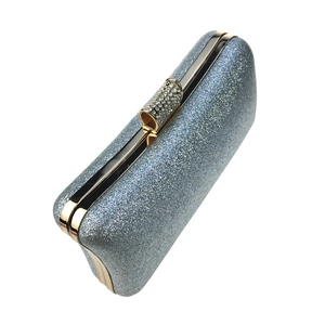 Macro detail of silver glitter evening clutch featuring rhinestone clasp and gold metal trim