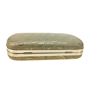 Close-up of golden scale texture on evening clutch with metallic frame detail