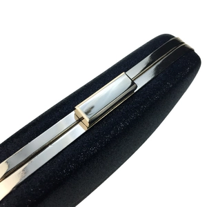 Detailed close-up of the black glitter fabric and silver metal clasp of this evening clutch