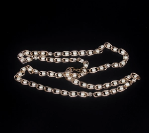 Detail of gold chain necklace featuring oval hollow links with white round pearls