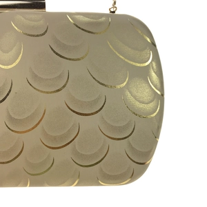 Detail of evening clutch featuring golden fish scale texture and metallic chain strap