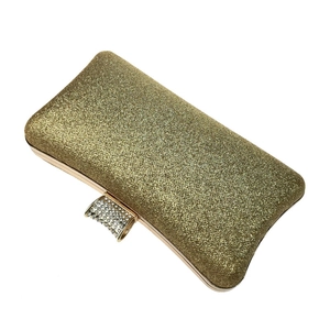 Detailed view of the sparkling gold glitter fabric and rhinestone clasp of the evening clutch
