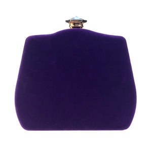 Macro detail of purple velvet clutch featuring a gold metal clasp with a crystal gemstone