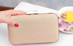 Gros plan sur la pochette de soirée dorée pailletée avec fermoir rectangulaire en métal