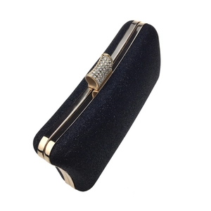 Close-up of black glitter evening bag featuring gold metal frame and rhinestone clasp