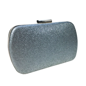 Macro shot of silver glitter material and sleek metal frame on a square evening clutch