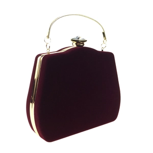 Detailed view of burgundy velvet evening bag with gold metal handle and diamond clasp