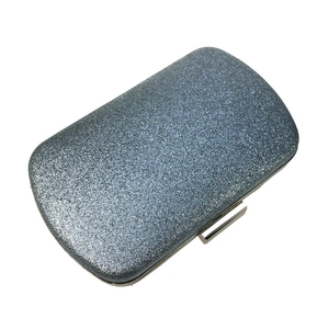 Detail of navy blue glitter fabric texture and silver metal clasp on square evening clutch