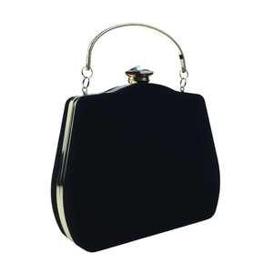 Detail of black velvet trapezoid evening bag with gold metal handle and gem clasp