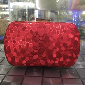 Detail of red water cube evening clutch with mosaic texture and golden metal clasp