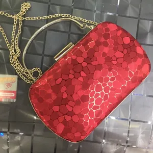 Detail of red geometric pebble textured leather clutch with gold metal chain strap