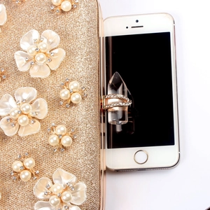 Close-up of golden evening clutch featuring 3D pearl flowers and sparkling crystals