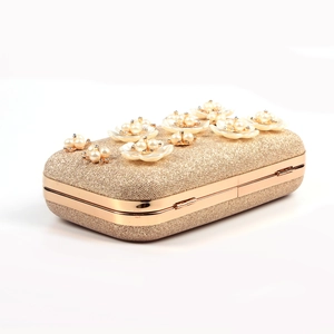 Macro detail of golden sequin evening clutch featuring 3D pearl flower ornaments and metallic clasp