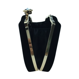 Detail of black velvet gourd clutch bag featuring gold metal frame and jewel clasp