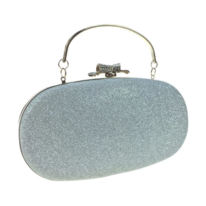 Detail of silver sequin evening bag featuring a rhinestone bow clasp and gold metal handle