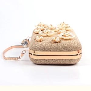 Detail of evening clutch bag featuring 3D floral pearls and gold metallic handle
