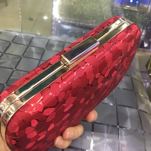 Detail of red clutch bag with geometric 3D texture and gold metal clasp frame