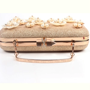 Detail of evening clutch featuring 3D ivory flowers with faux pearls and gold sequins