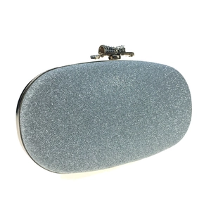 Macro view of silver glitter clutch bag featuring a bowtie rhinestone top clasp