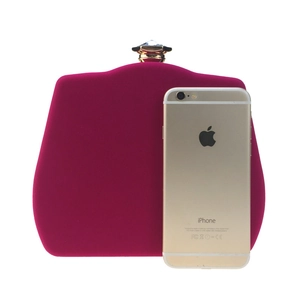 Detailed view of fuchsia velvet clutch with jewel clasp next to a phone for size comparison