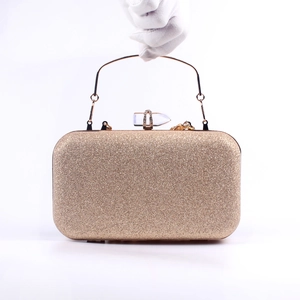 Elegant gold glitter evening clutch bag with crystal buckle held by a hand in white glove