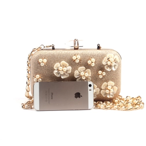 Detail of floral evening bag with pearls and golden chain showing scale with a phone