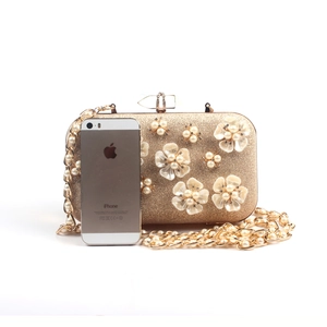 Macro view of golden evening clutch featuring 3D pearl flowers and fine glitter finish