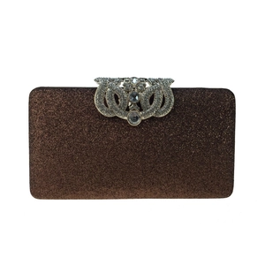 Close-up of bronze glitter evening clutch with ornate silver rhinestone wavy clasp detail