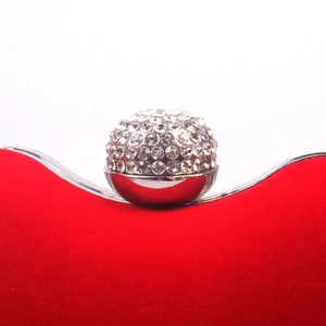 Close-up of red evening clutch with silver rhinestone-encrusted clasp and velvet texture