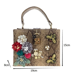 Détail du sac à main motif serpent avec fleurs 3D et broderies d'abeilles élégantes